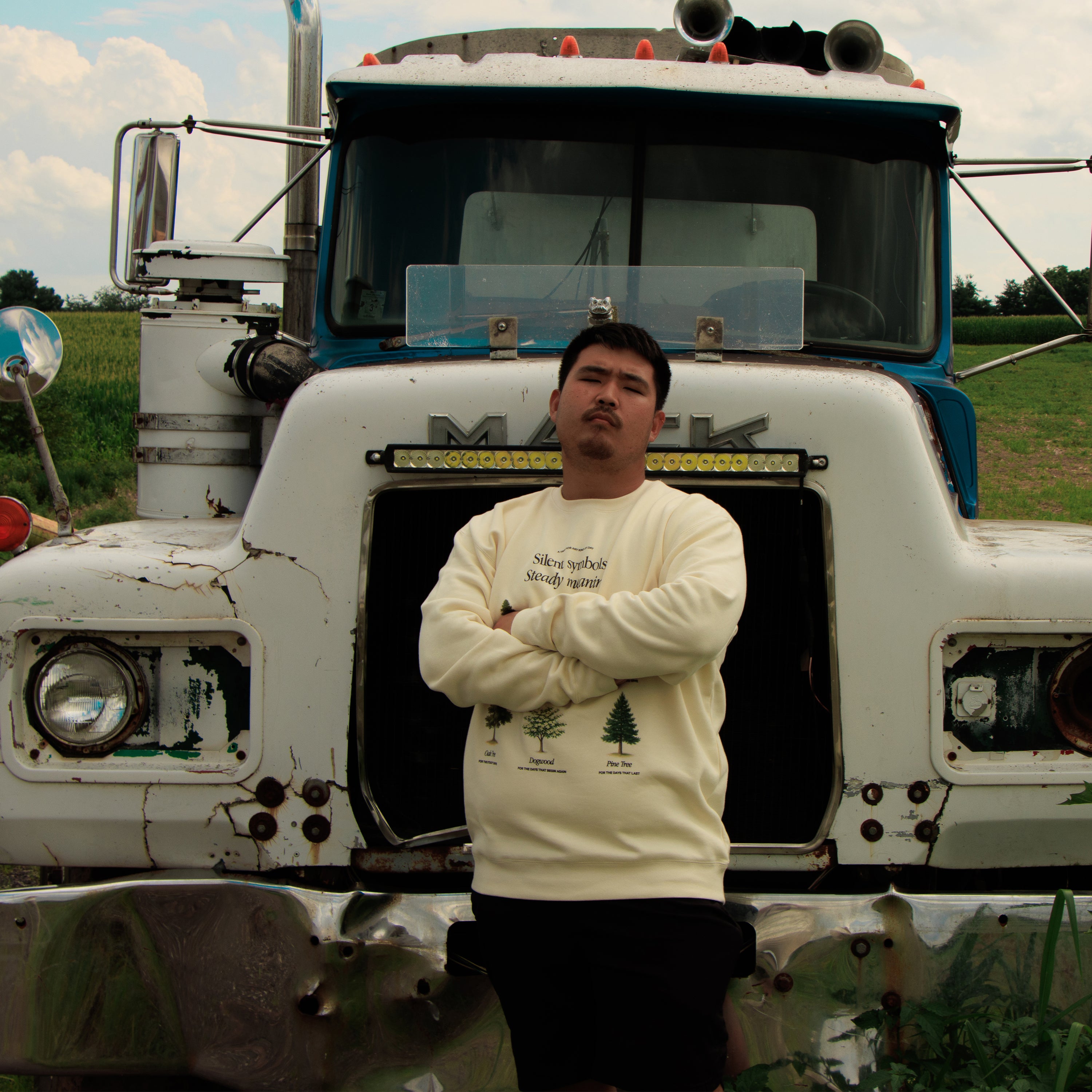 Man standing in front of a large truck with a field in the background