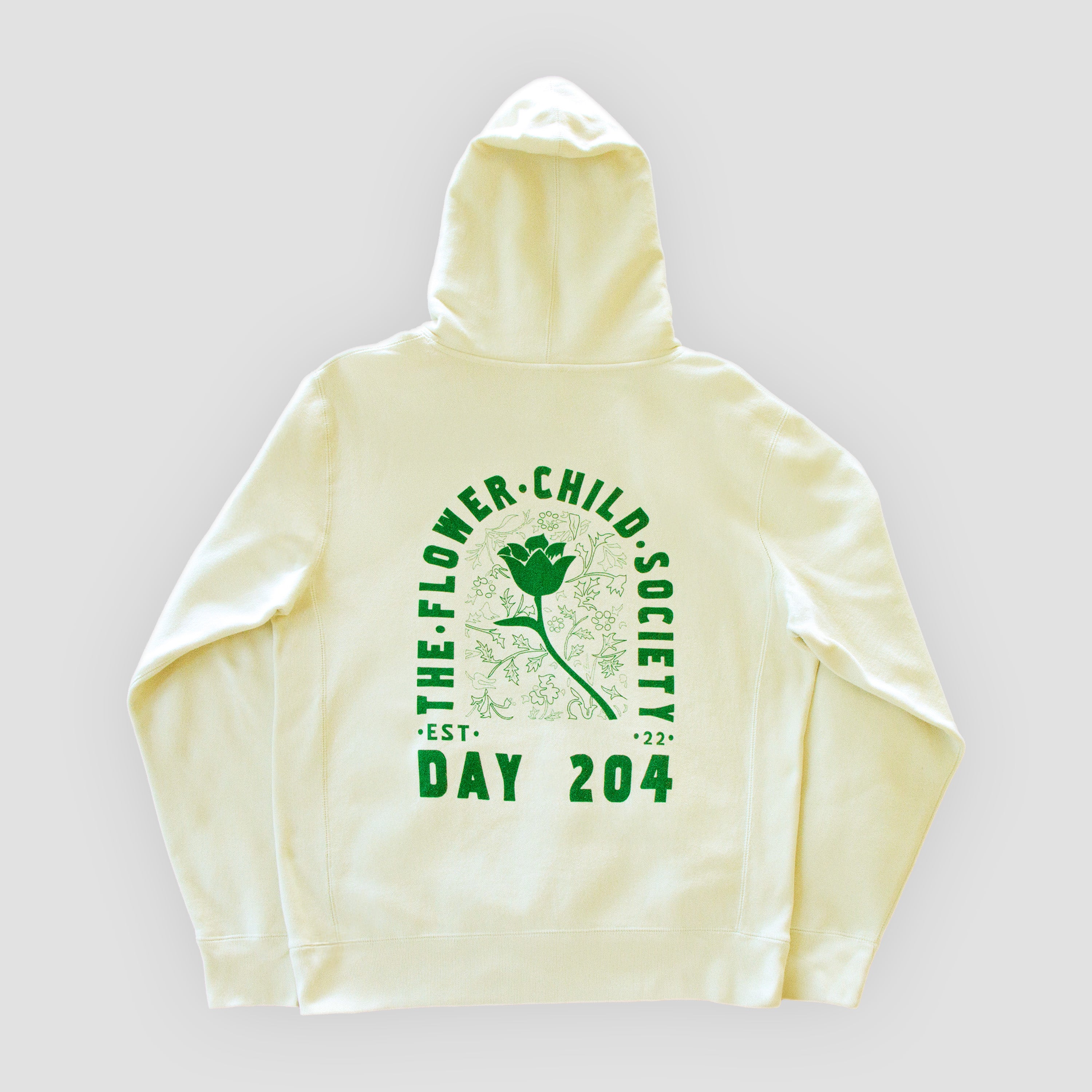 Cream-colored hoodie with green text and flower graphic on a light gray background