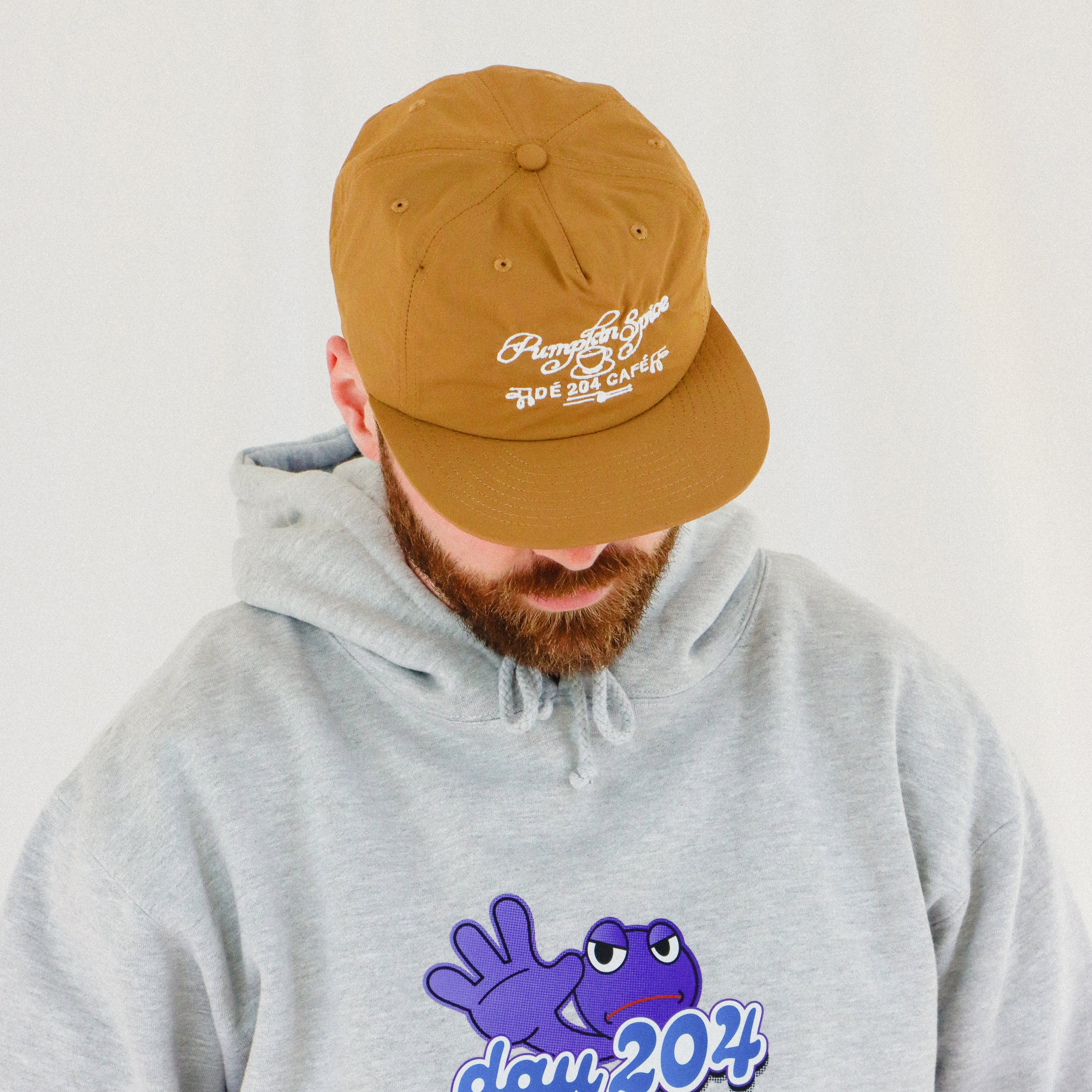 Person wearing a brown cap and gray hoodie with a blue graphic design on a light background