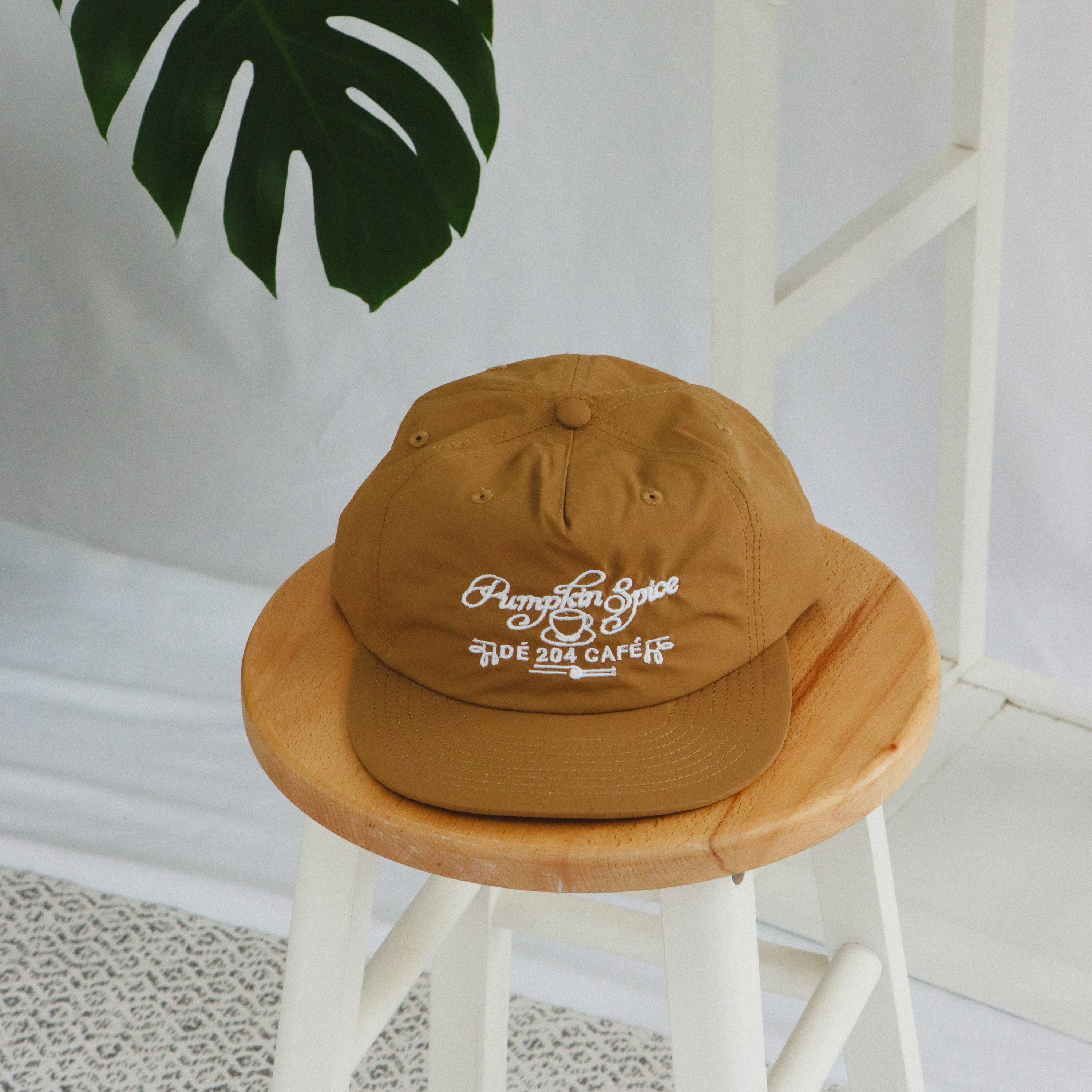 Brown cap with white text on a wooden stool with a plant in the background
